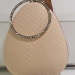 Bolso rigido color beige, con asa redonda y cadena para colgar, medidas 21×18 cms. (1100000014)